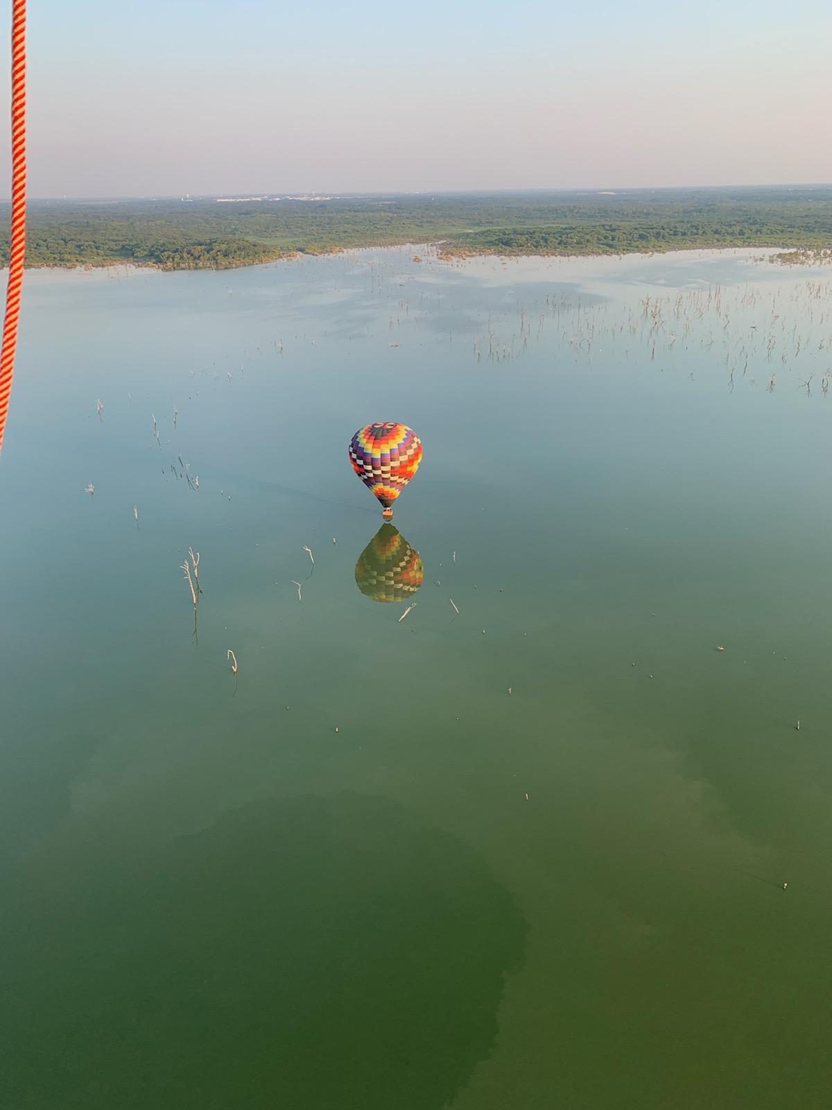 A balloon reflection crossing a North Texas lake, seen from the basket