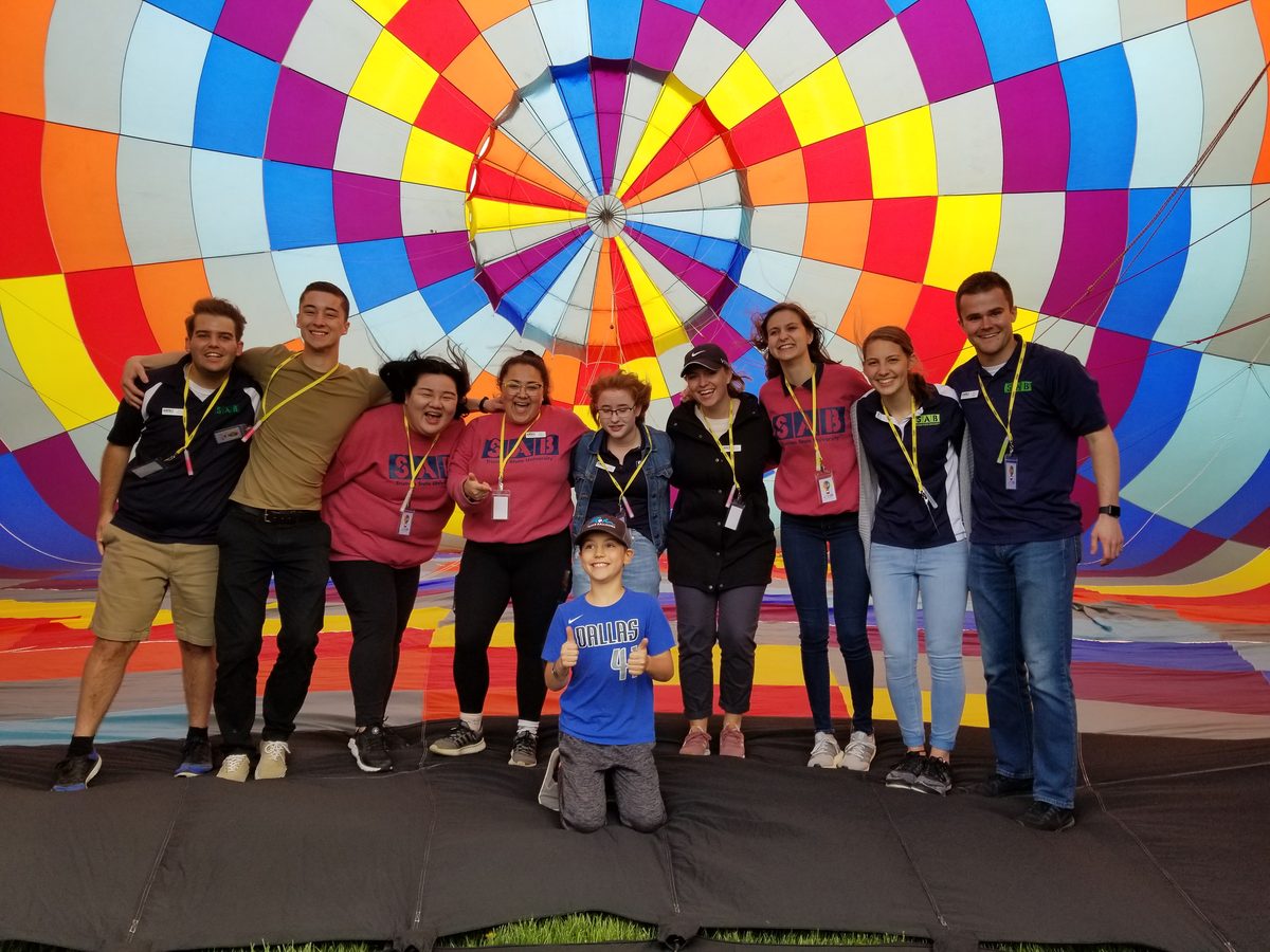 A group poses inside the mouth of the balloon envelope at a Rohr Balloons team-building event