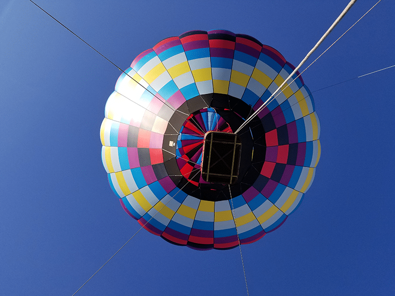 Looking up at a tethered hot air balloon over the crowd